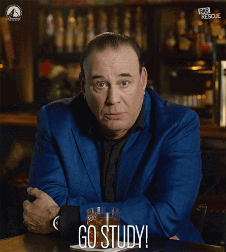 A Man In A Blue Suit Sits At A Table With A Glass Of Whiskey And The Words Go Study Below Him GIF