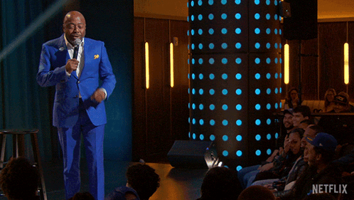A Man In A Blue Suit Stands In Front Of A Crowd With The Words " Everybody Gets A Therapist " GIF