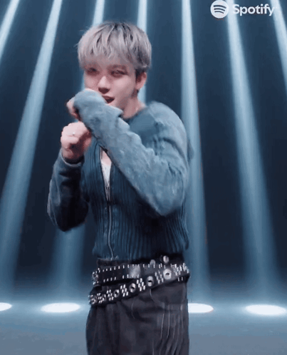 A Man In A Blue Sweater And Black Pants Is Dancing In Front Of Spotify GIF