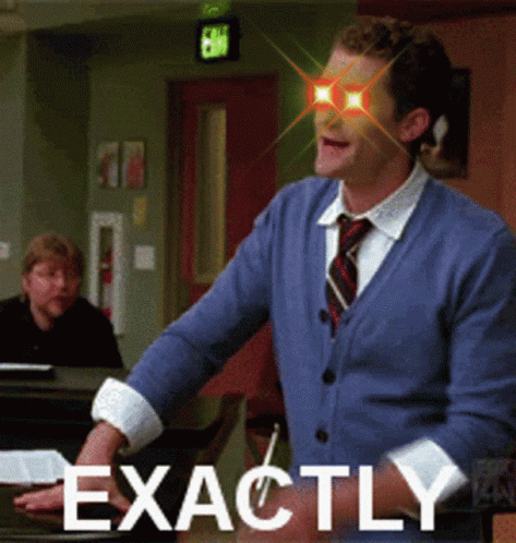 Man In Blue Sweater And Tie Standing By Piano GIF