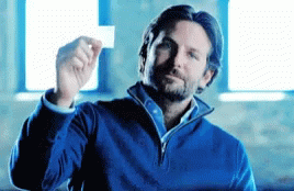 A Man In A Blue Sweater Is Holding Up A White Card GIF