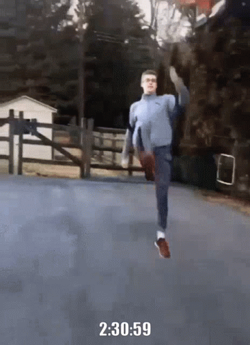 A Man In A Blue Sweater Is Running On A Road With The Time Of 2 : 30 : 59 GIF