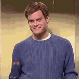 Man In Blue Sweater Smiling In Front Of Wall GIF