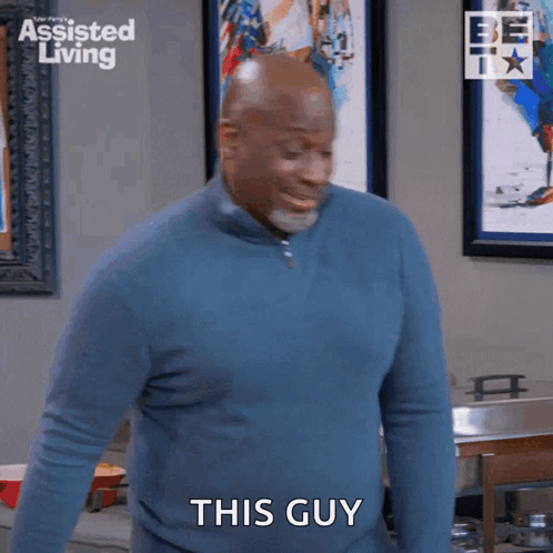 A Man In A Blue Sweater Is Standing In A Kitchen And Saying This Guy GIF