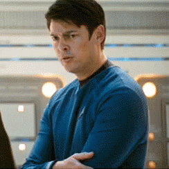A Man In A Blue Sweater Is Standing In Front Of A Laptop Computer . GIF