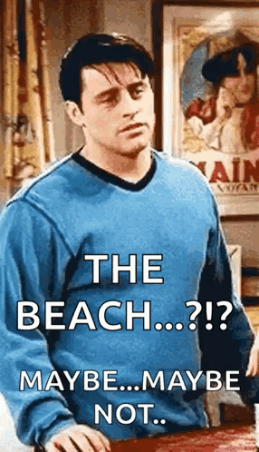 A Man In A Blue Sweater Is Standing In Front Of A Table With The Words The Beach Maybe Maybe Not . GIF