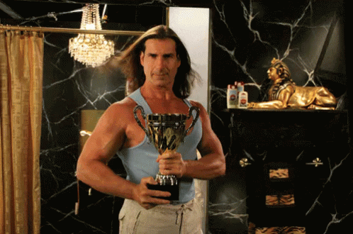 A Man In A Blue Tank Top Holds A Trophy That Says " Winner " On It GIF