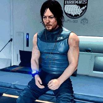 A Man In A Blue Tank Top Is Sitting In Front Of A Wall That Says Bridges GIF