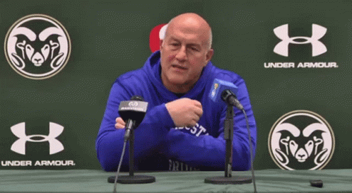 a man in a blue under armour sweatshirt is sitting at a table