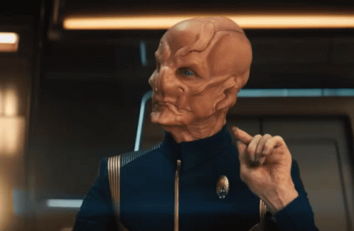 A Man In A Blue Uniform Has A Star Trek Logo On His Jacket GIF