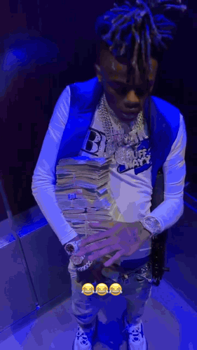 A Man In A Blue Vest Is Holding A Stack Of Money In His Hands . GIF