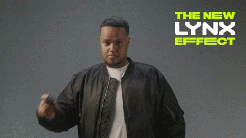 A Man In A Bomber Jacket Is Standing In Front Of A Sign That Says The New Lynx Effect GIF