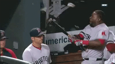 A Man In A Boston Jersey Is Swinging A Bat At Another Man GIF