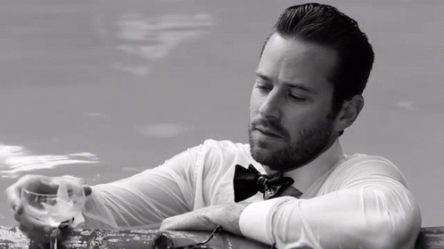 A Man In A Bow Tie Is Holding A Glass GIF