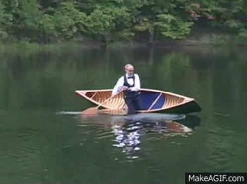 A Man In A Bow Tie Is Rowing A Boat On A Lake GIF