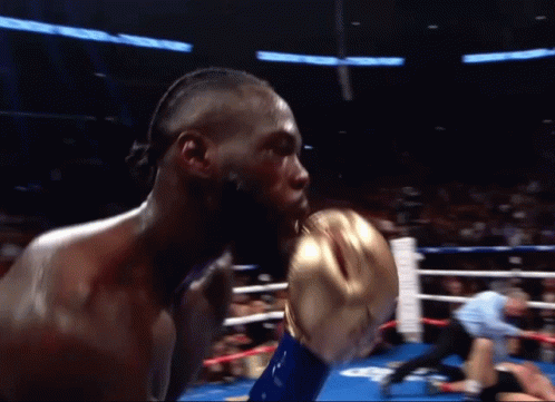 A Man In A Boxing Ring With A Referee Behind Him GIF