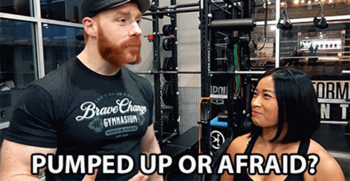 A Man In A Brave Change Gym Shirt Talks To A Woman In A Gym GIF