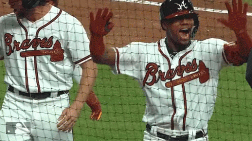 A Man In A Braves Jersey Is Waving His Hands In The Air GIF