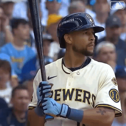 a man in a brewers jersey is holding a baseball bat .