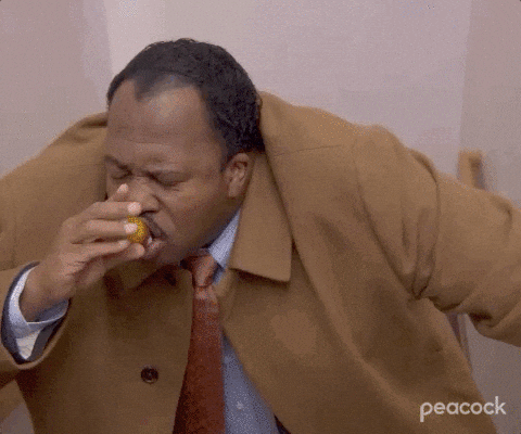 A Man In A Brown Coat And Tie Is Eating A Donut . GIF