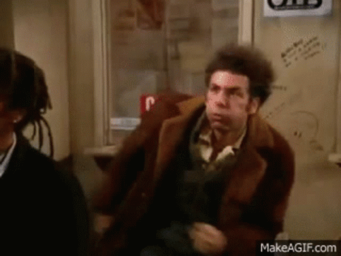 A Man In A Brown Coat Is Sitting Next To A Woman In A Chair . GIF