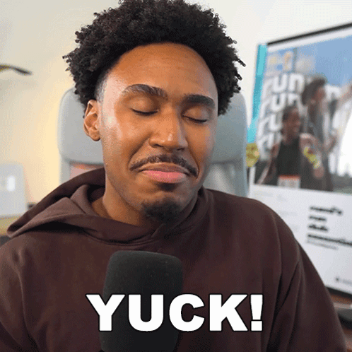 A Man In A Brown Hoodie Is Talking Into A Microphone And Says Yuck GIF