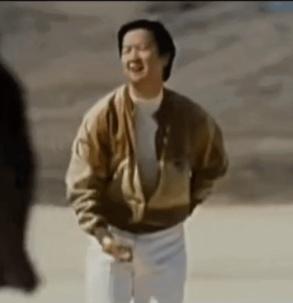 A Man In A Brown Jacket And White Pants Is Standing In A Desert . GIF