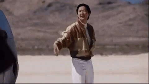 A Man In A Brown Jacket And White Pants Is Standing In A Desert . GIF