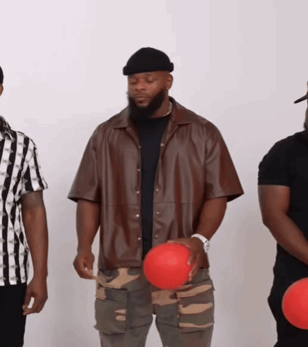 A Man In A Brown Jacket Holds A Red Ball In His Hand GIF