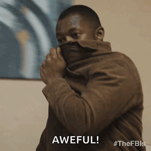 A Man In A Brown Jacket Is Covering His Face With His Jacket And The Word Awful Is Above Him GIF