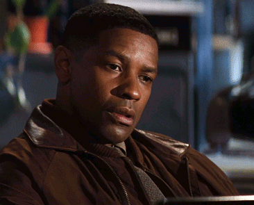 a man in a brown jacket is sitting at a desk