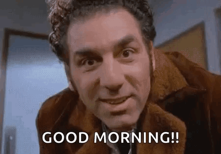 A Man In A Brown Jacket Is Smiling And Says `` Good Morning '' . GIF
