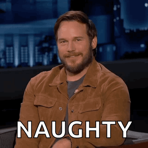A Man In A Brown Jacket Is Smiling With The Word Naughty Behind Him GIF