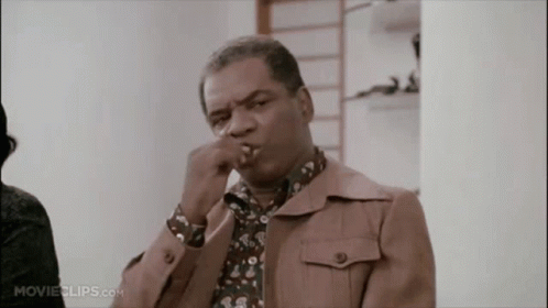 A Man In A Brown Jacket Is Smoking A Cigarette In A Movie Clip GIF