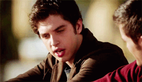 A Man In A Brown Jacket Is Talking To Another Man In A Red Sweater GIF