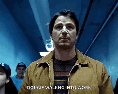 A Man In A Brown Jacket Is Walking Into A Dark Room . GIF