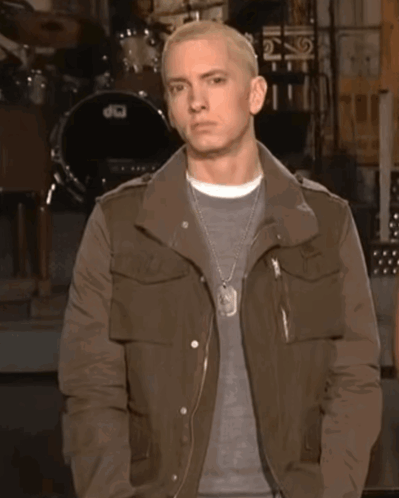 A Man In A Brown Jacket Stands In Front Of A Drum Set That Says Dw GIF