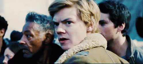 A Man In A Brown Jacket With A Fur Collar Stands In A Crowd GIF