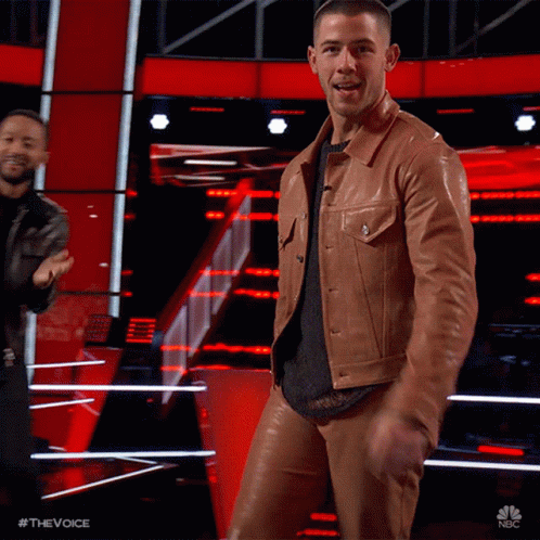 A Man In A Brown Leather Jacket And Pants Is Dancing On Stage GIF