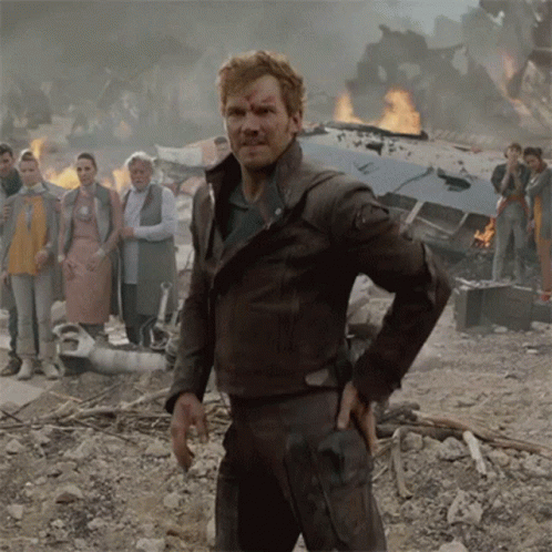 A Man In A Brown Leather Jacket Stands In Front Of A Burning Building GIF