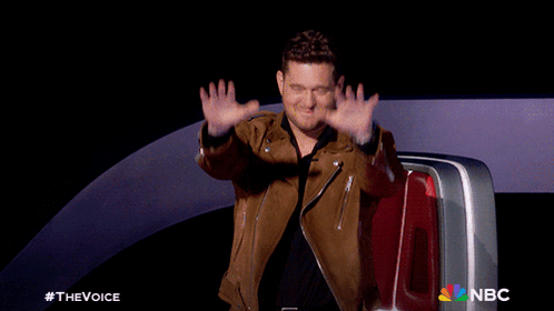 A Man In A Brown Leather Jacket Waves His Hands In Front Of A Nbc Logo GIF