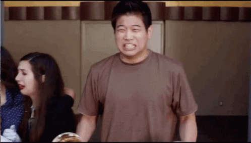 A Man In A Brown Shirt Is Making A Face GIF