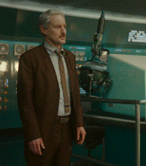 Man In Brown Suit Standing In Front Of Machine GIF