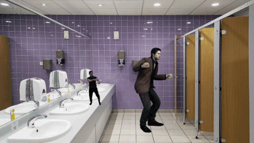 A Man In A Brown Suit Is Dancing In A Public Restroom GIF
