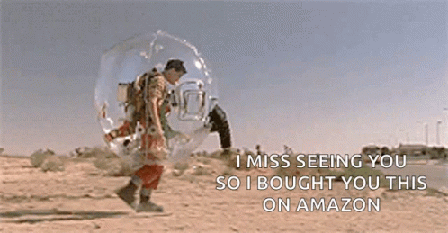 A Man In A Bubble Is Walking Down A Dirt Road . GIF