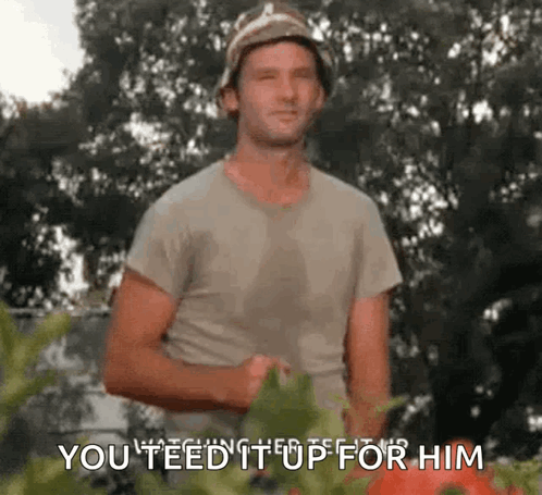 A Man In A Bucket Hat Is Standing In Front Of A Tomato Plant And Says `` You Feed It Up For Him '' . GIF