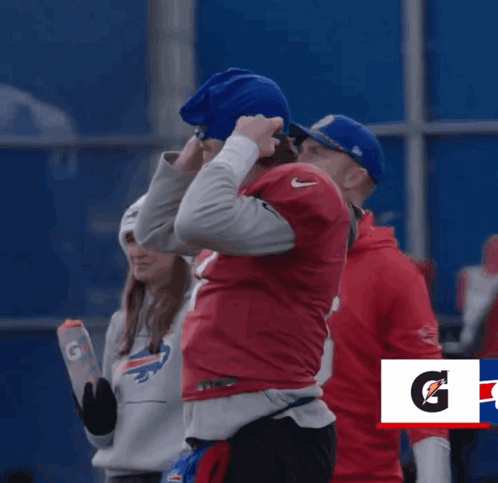 A Man In A Buffalo Bills Jersey Stands Next To Another Man GIF