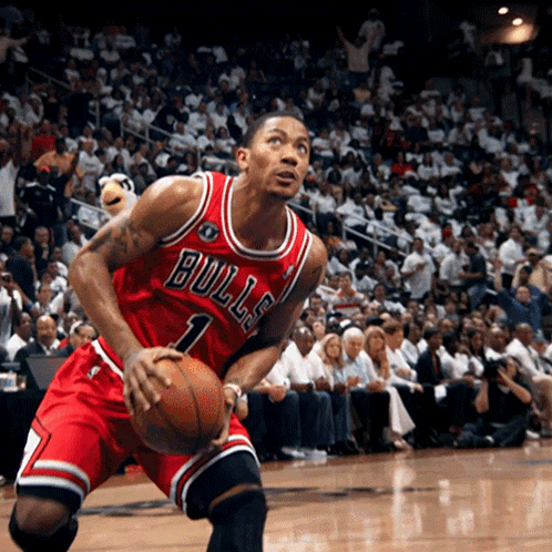A Man In A Bulls Jersey Is Holding A Basketball In Front Of A Crowd GIF