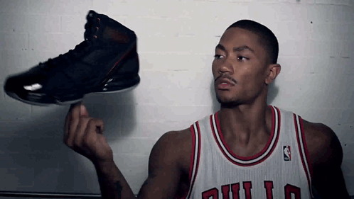 A Man In A Bulls Jersey Is Holding A Black Shoe GIF