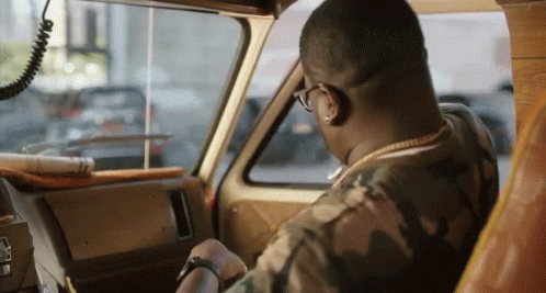 a man in a camo shirt is driving a vehicle